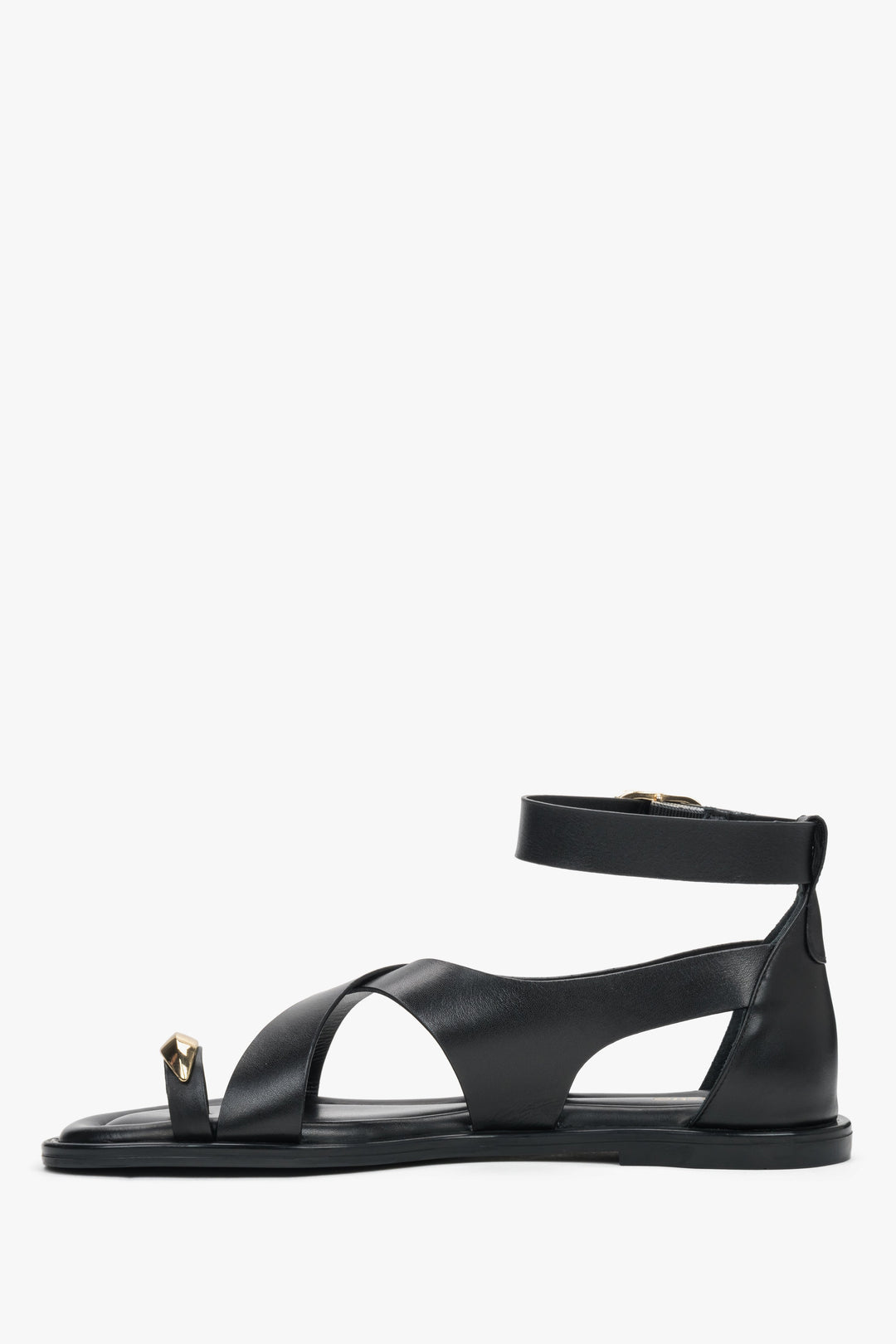 Black leather women’s Estro sandals with a gold toe ring detail - side view. 
