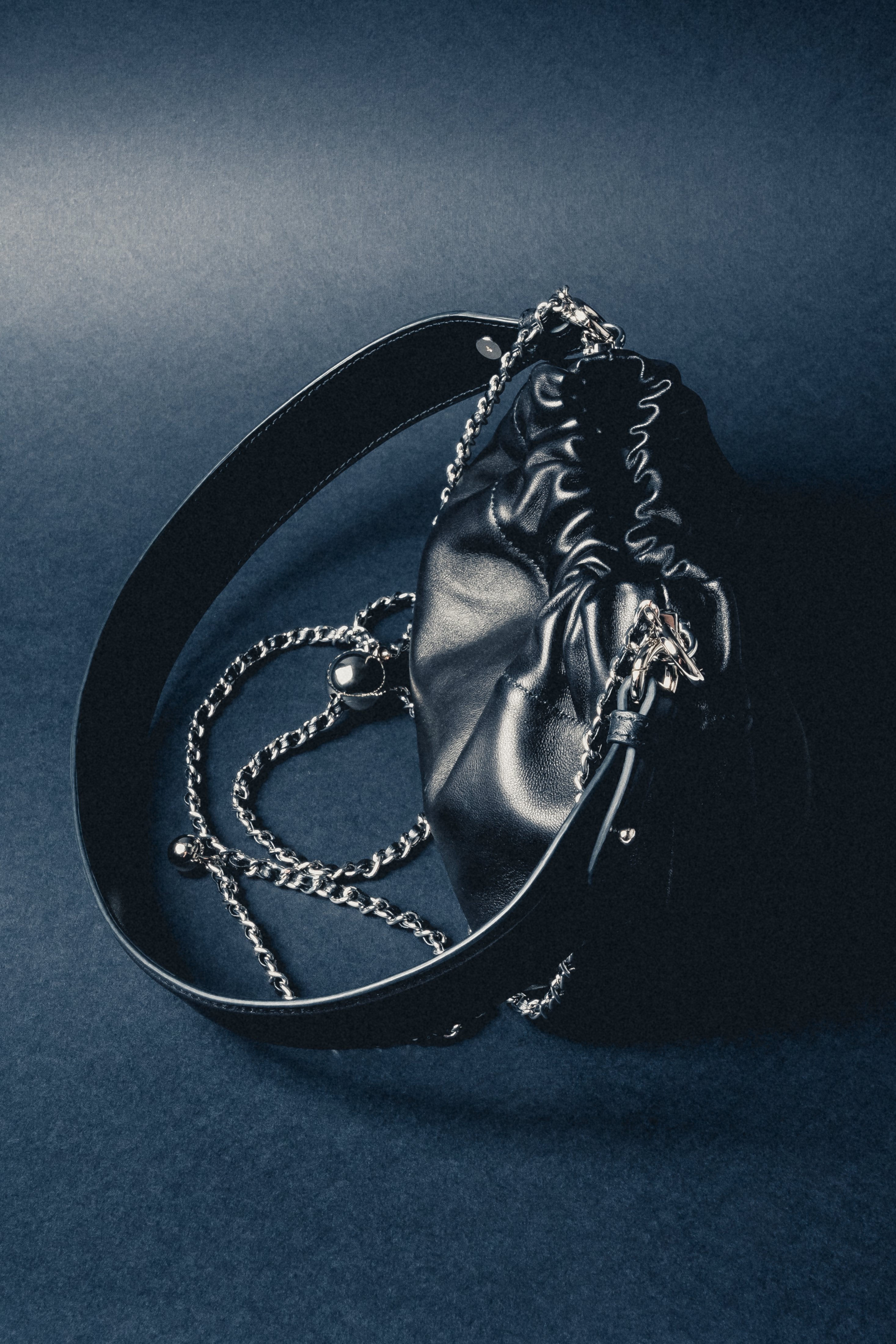Close-up of women's black leather shoulder bag with silver chain detail