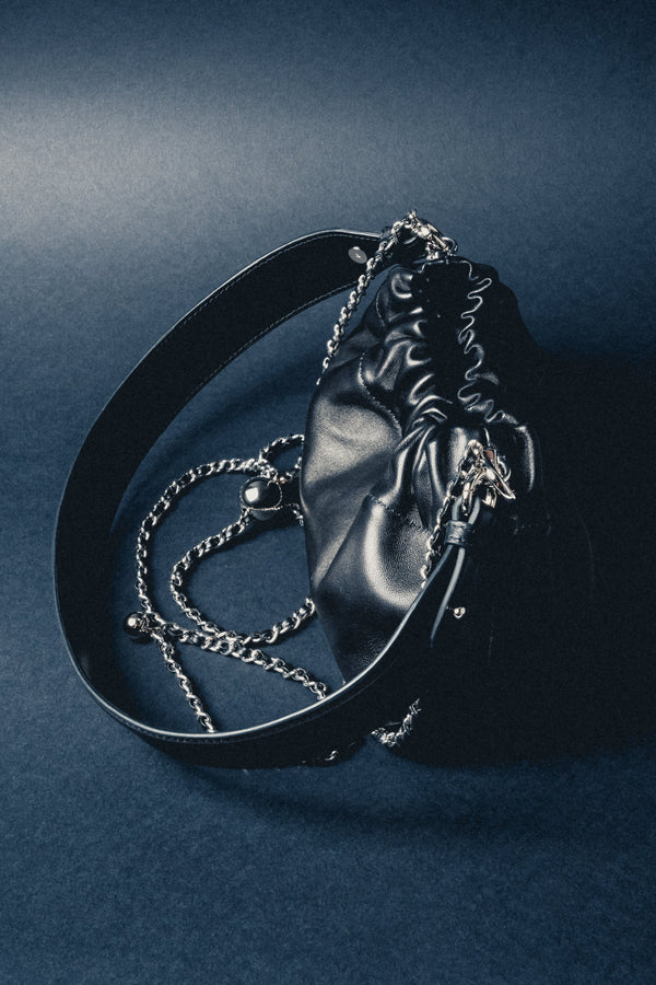 Close-up of women's black leather shoulder bag with silver chain detail