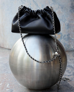 Close-up of gathered top on women's black leather shoulder bag