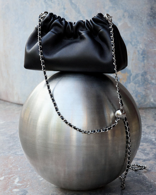Close-up of gathered top on women's black leather shoulder bag