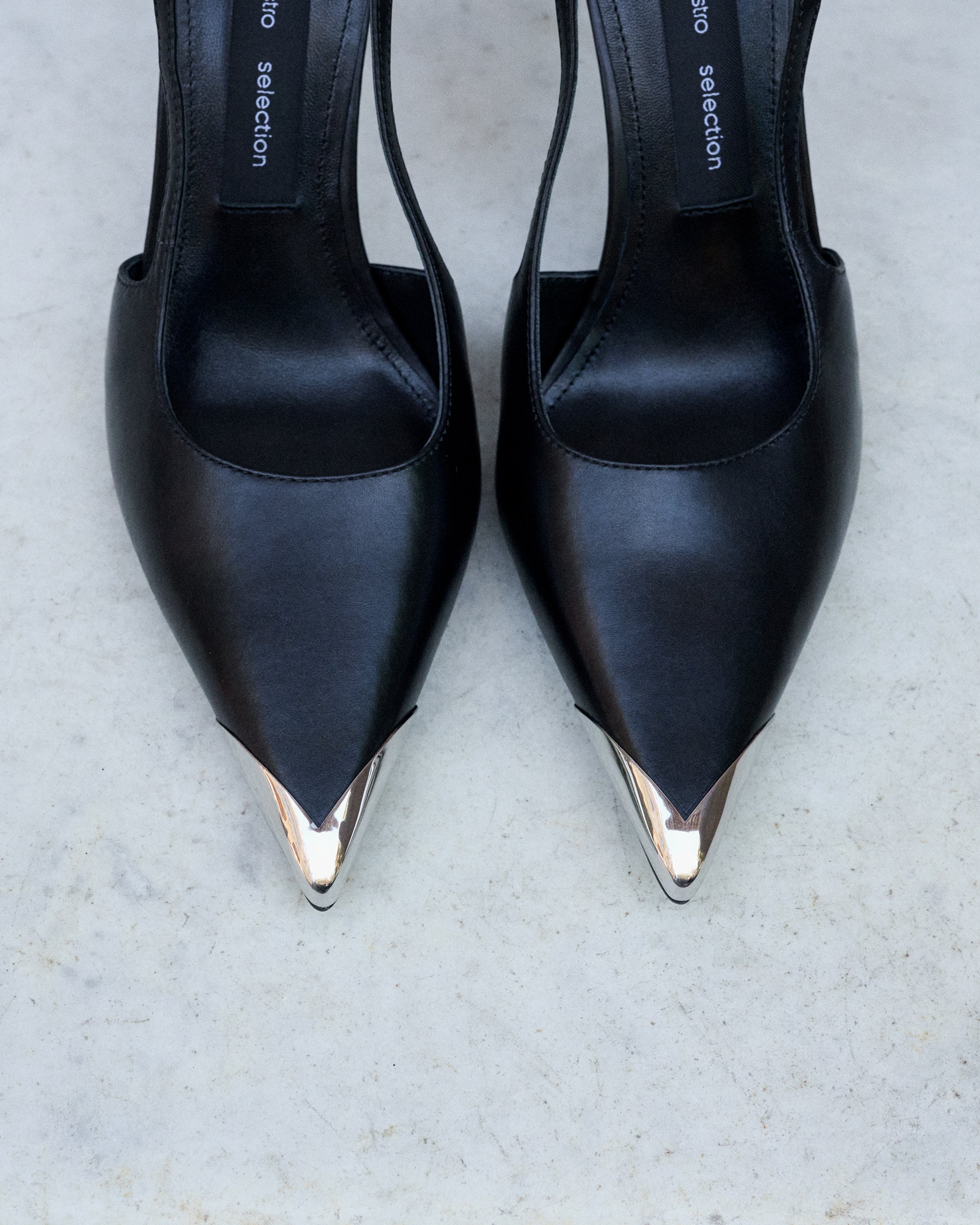 Profile of women's black leather slingback stilettos with a thin heel at the front