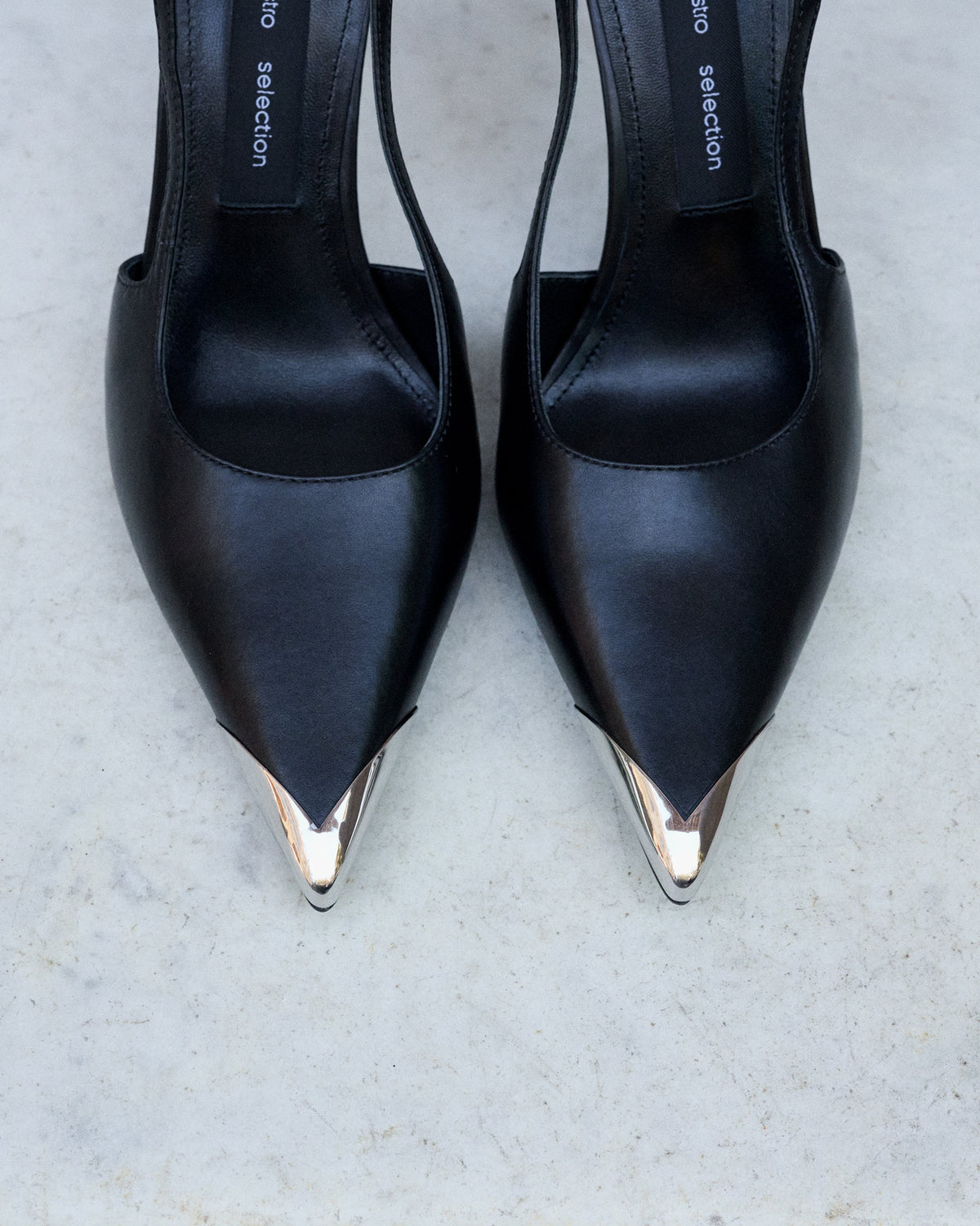 Profile of women's black leather slingback stilettos with a thin heel at the front