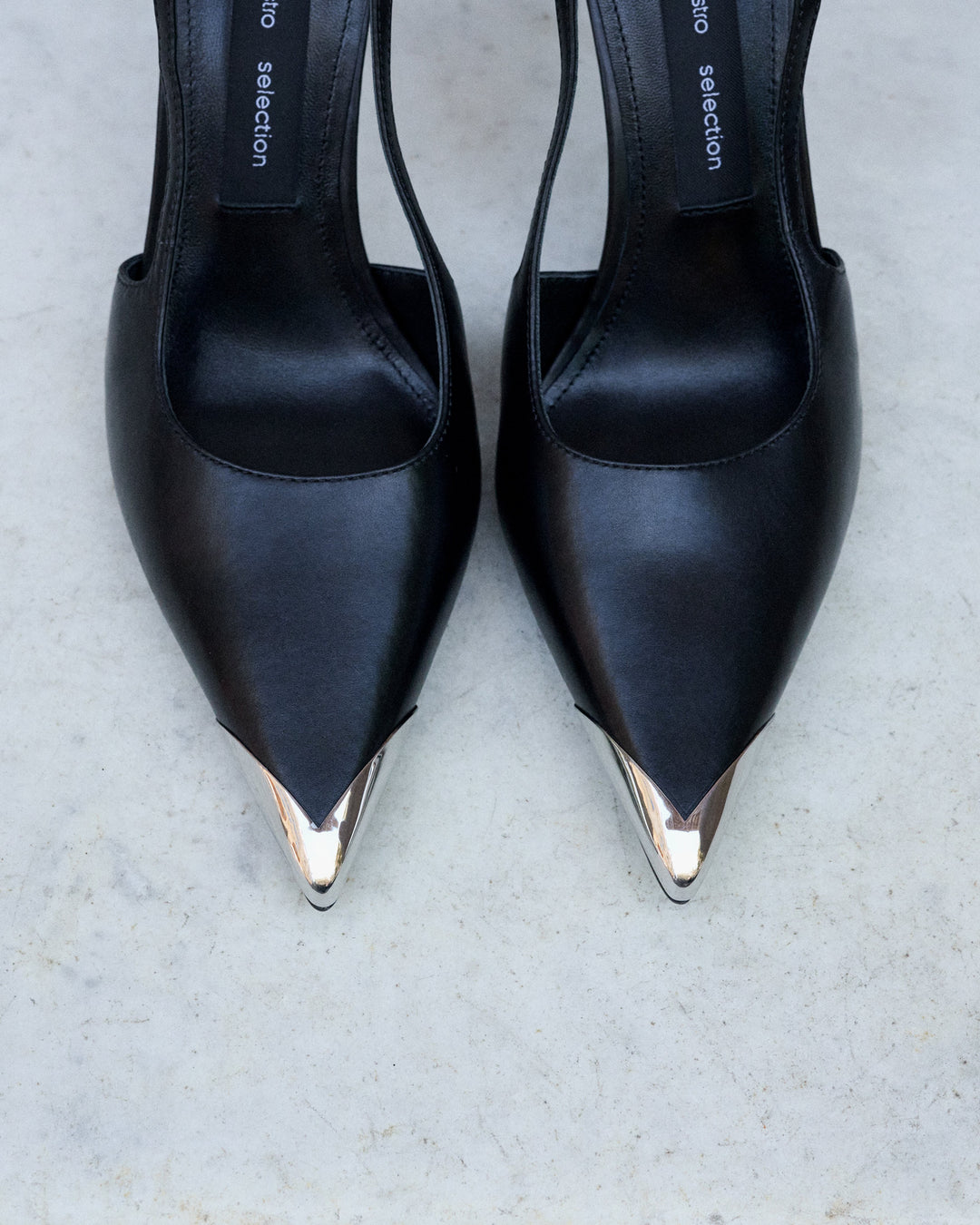 Profile of women's black leather slingback stilettos with a thin heel at the front