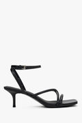 Women’s black leather stiletto sandals by Estro with thin crossing straps.
