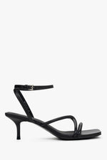 Women’s black leather stiletto sandals by Estro with thin crossing straps.