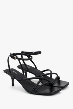 Side view of women’s black stiletto sandals with slim leather straps.