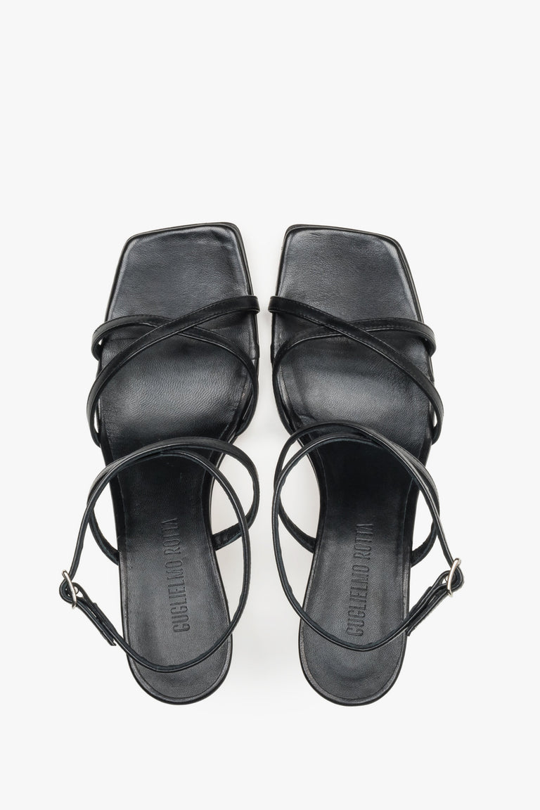 Close-up of the criss-crossing leather straps and stable flare heel on luxury black sandals.