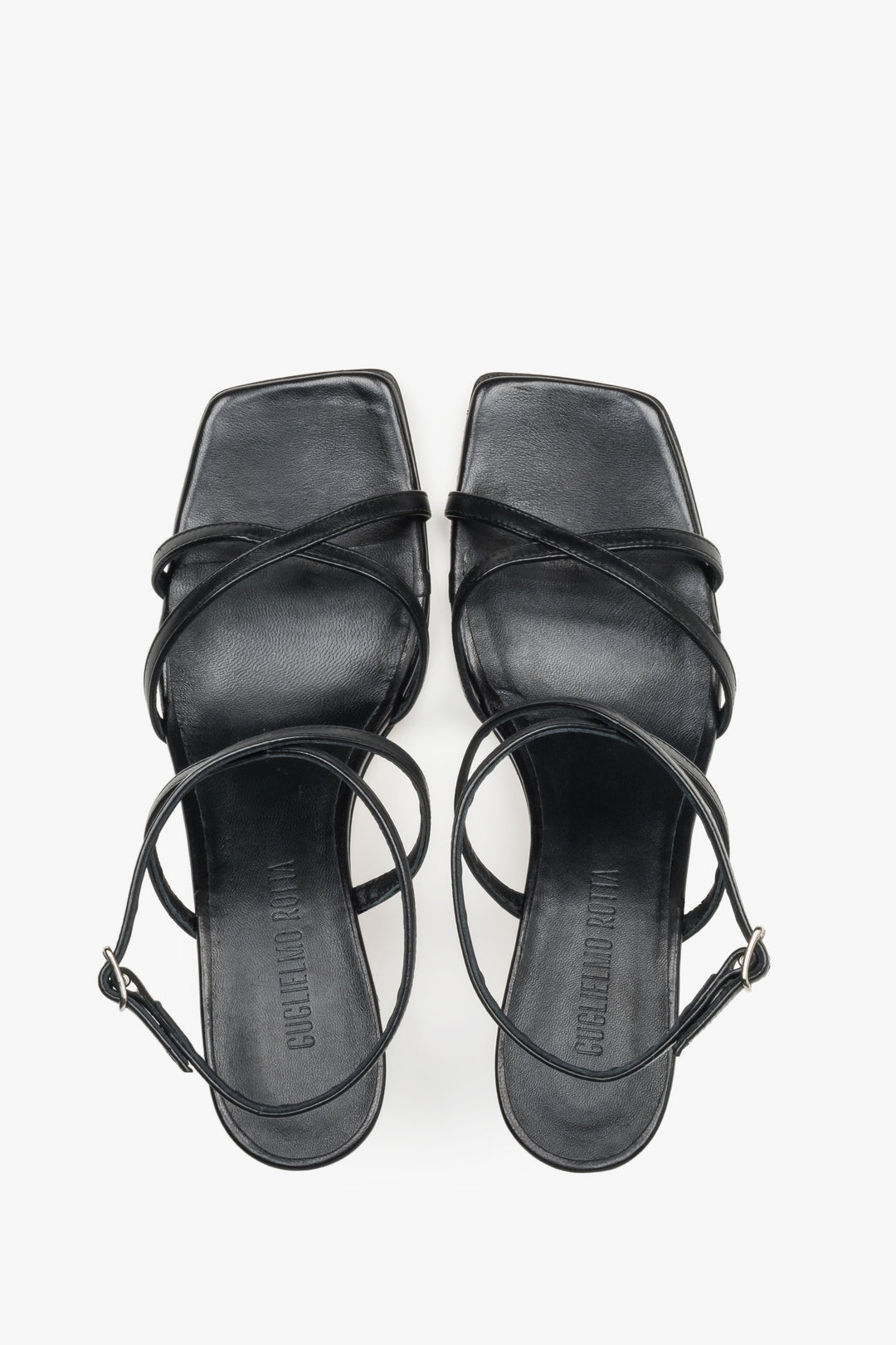 Close-up of the criss-crossing leather straps and stable flare heel on luxury black sandals.