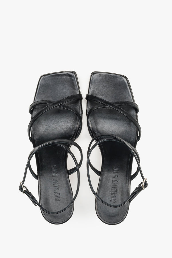 Close-up of the criss-crossing leather straps and stable flare heel on luxury black sandals.