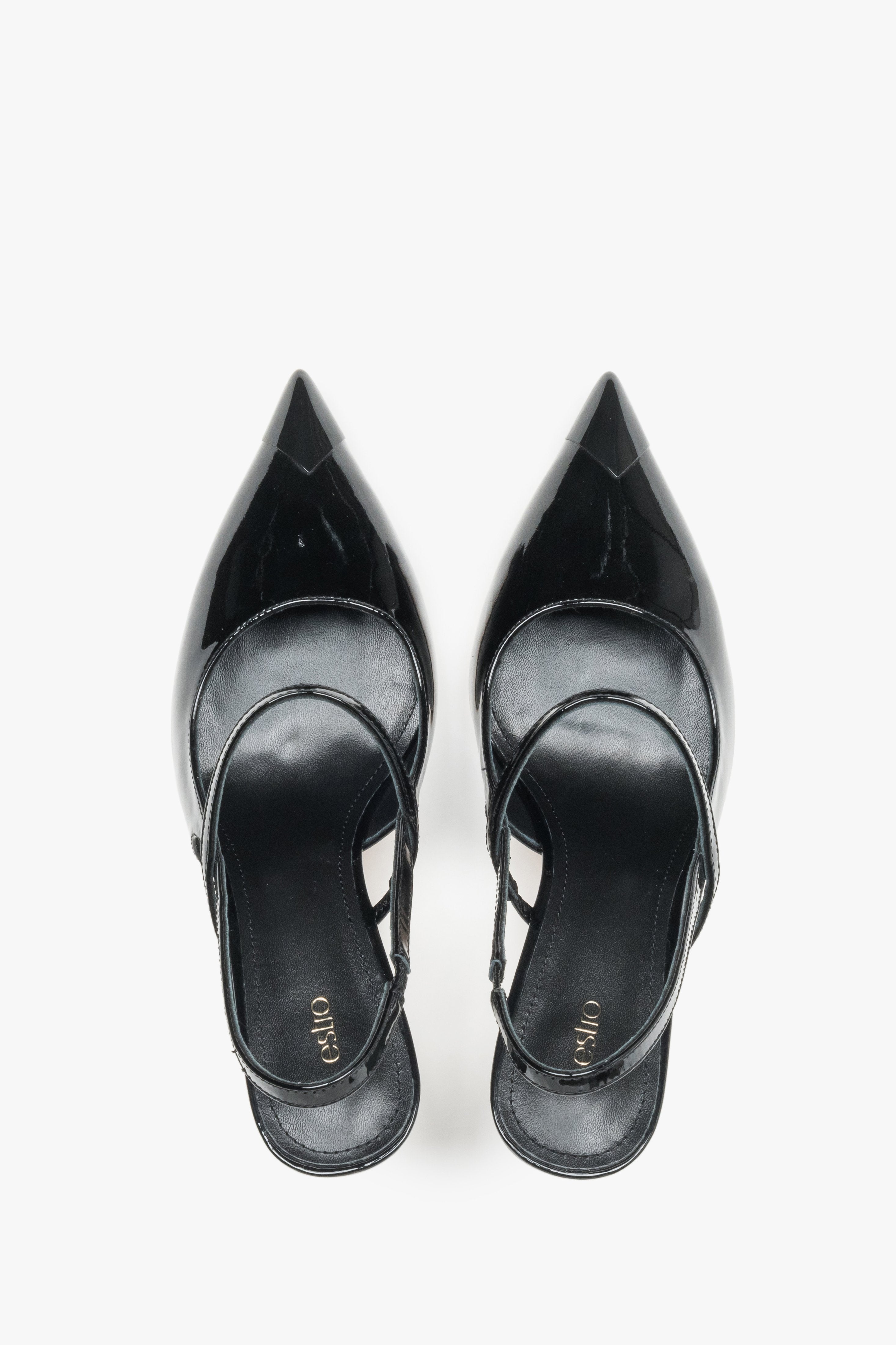 Close-up of the mirror-shine black patent leather and elegant strap detail on stiletto pumps.