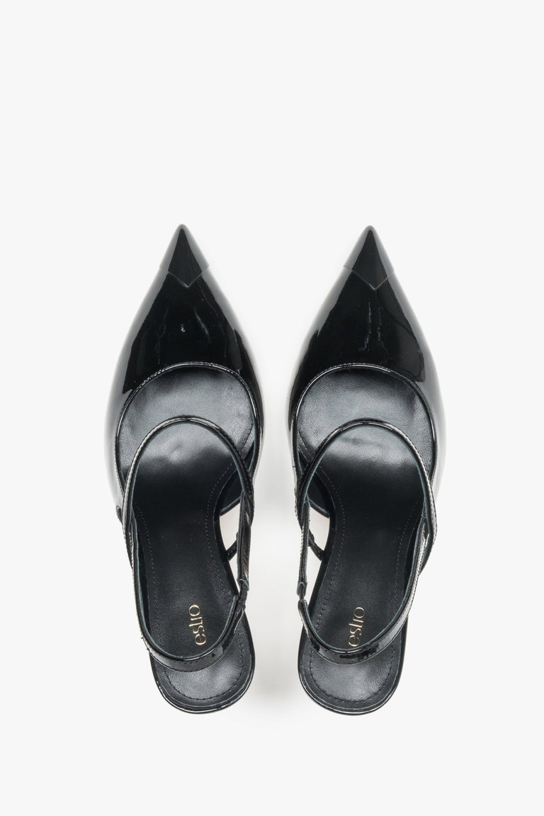 Close-up of the mirror-shine black patent leather and elegant strap detail on stiletto pumps.