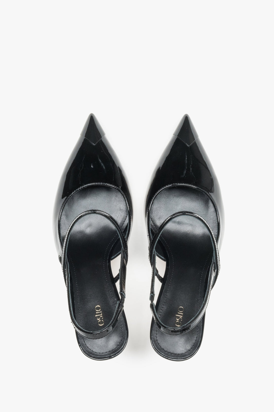 Close-up of the mirror-shine black patent leather and elegant strap detail on stiletto pumps.