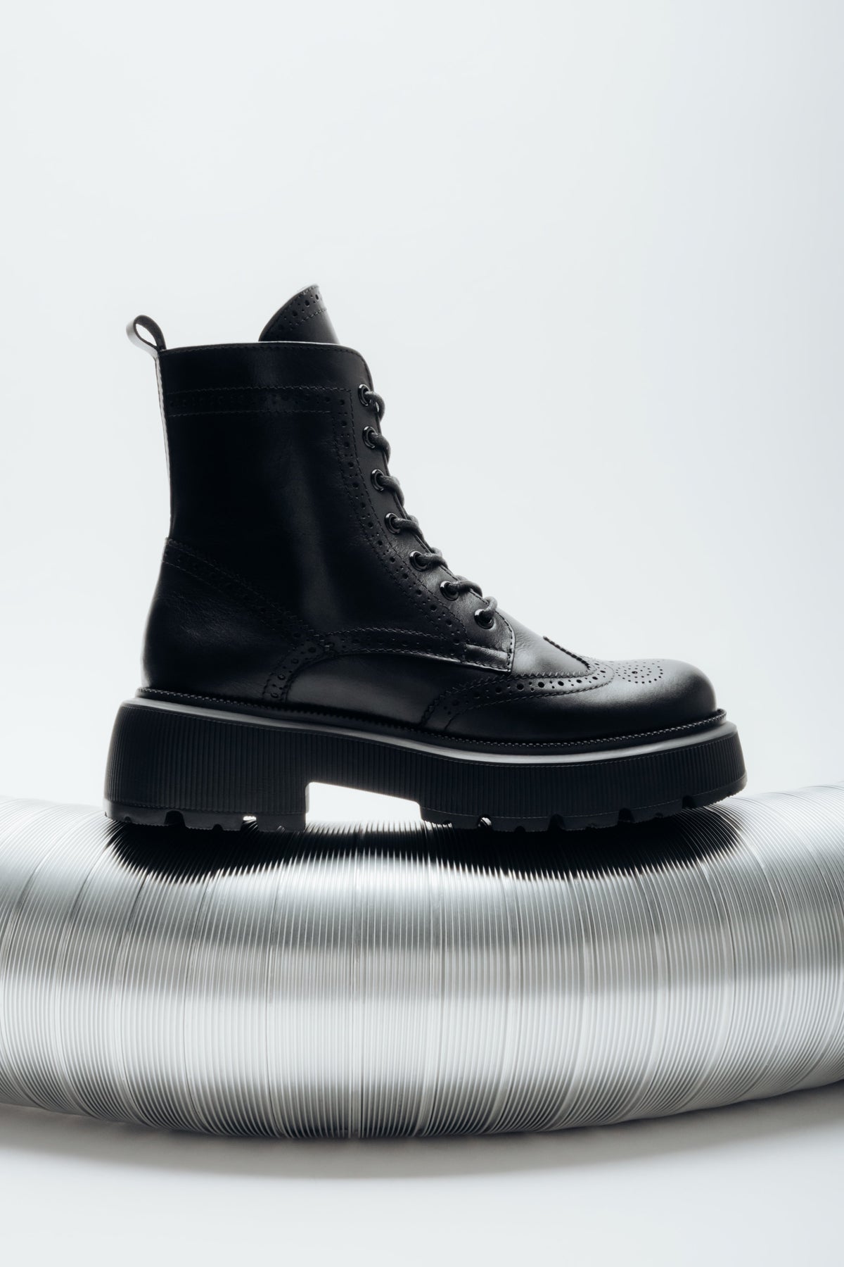 Black natural leather ankle boots featuring folk-style laser perforation details, Estro.