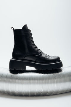 Black natural leather ankle boots featuring folk-style laser perforation details, Estro.