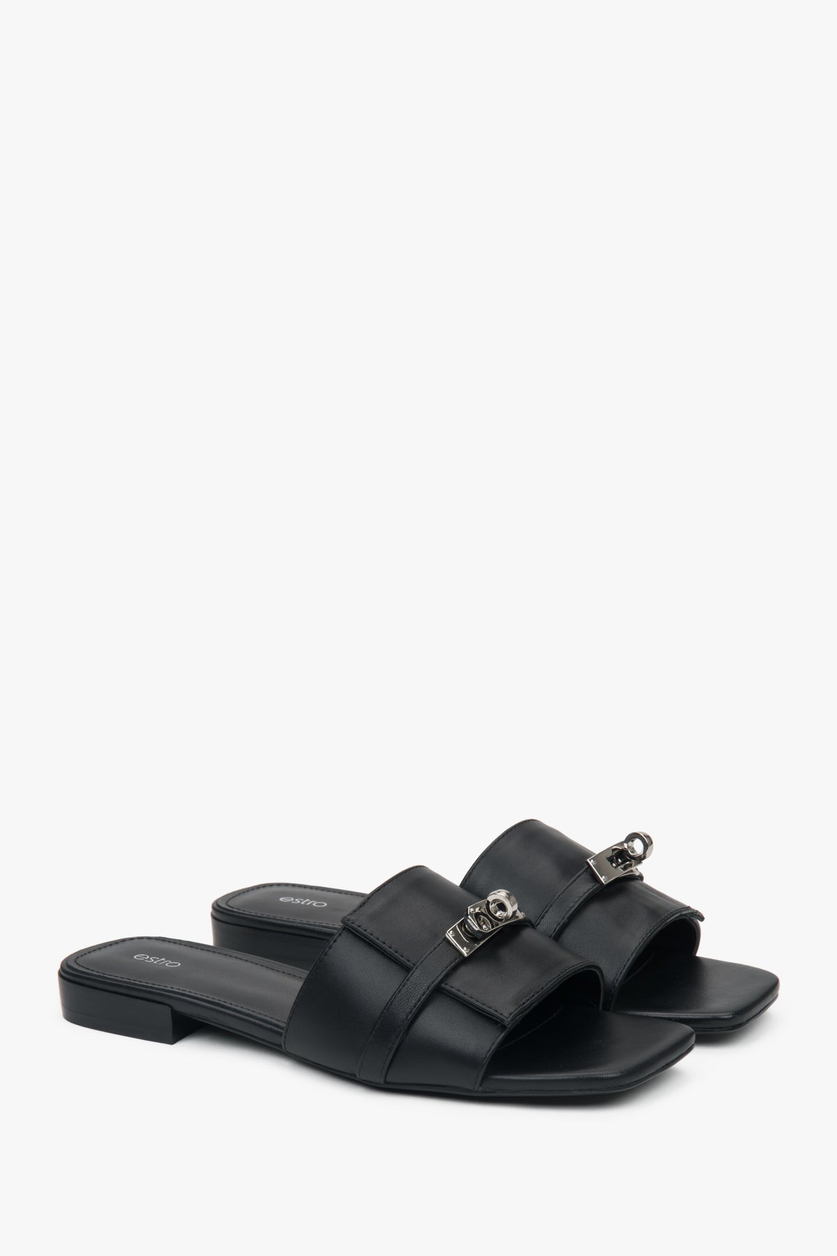 Elegant black Estro women's slide sandals, adorned with a silver embellishment, perfect for everyday wear, featuring a comfortable flat heel.