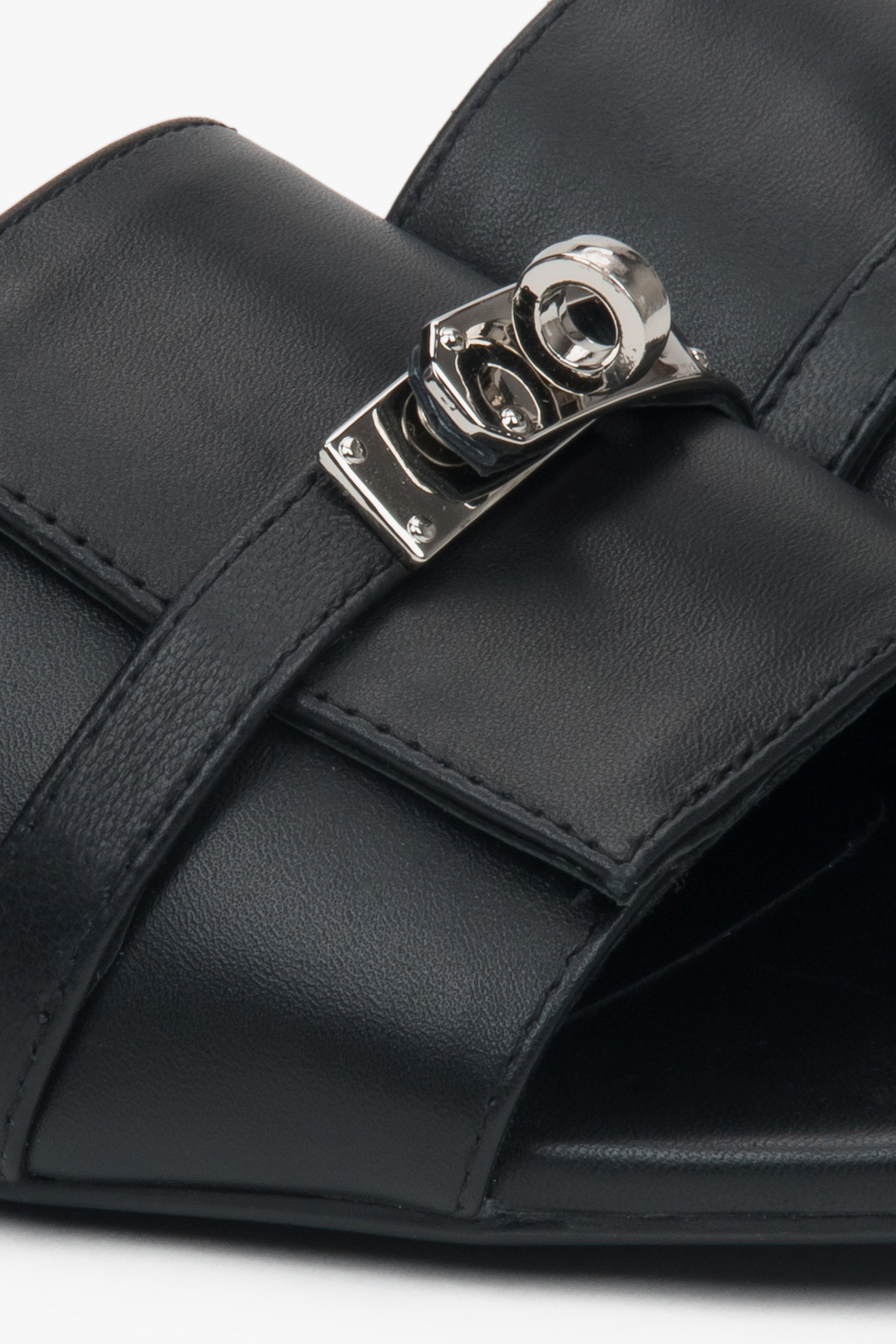 Black flat-heeled slides with a silver embellishment from Estro – a blend of comfort, subtle elegance, and versatile design, close-up on details.
