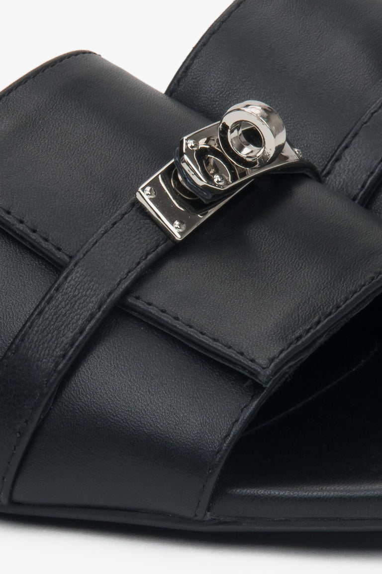 Black flat-heeled slides with a silver embellishment from Estro – a blend of comfort, subtle elegance, and versatile design, close-up on details.