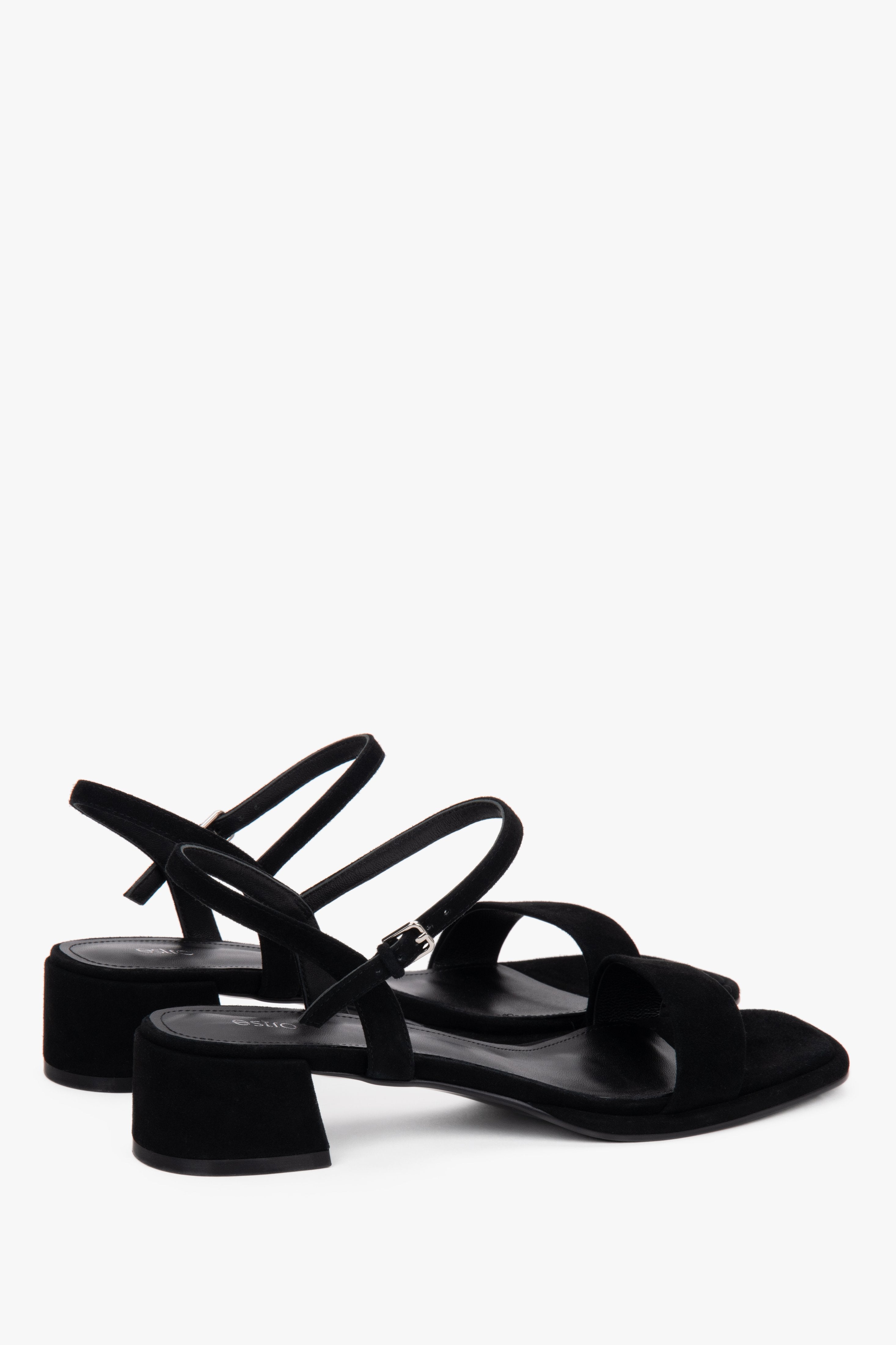Close-up of the deep black velour texture and soft buckle on women's sandals.