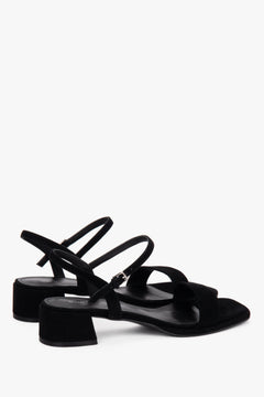 Close-up of the deep black velour texture and soft buckle on women's sandals.