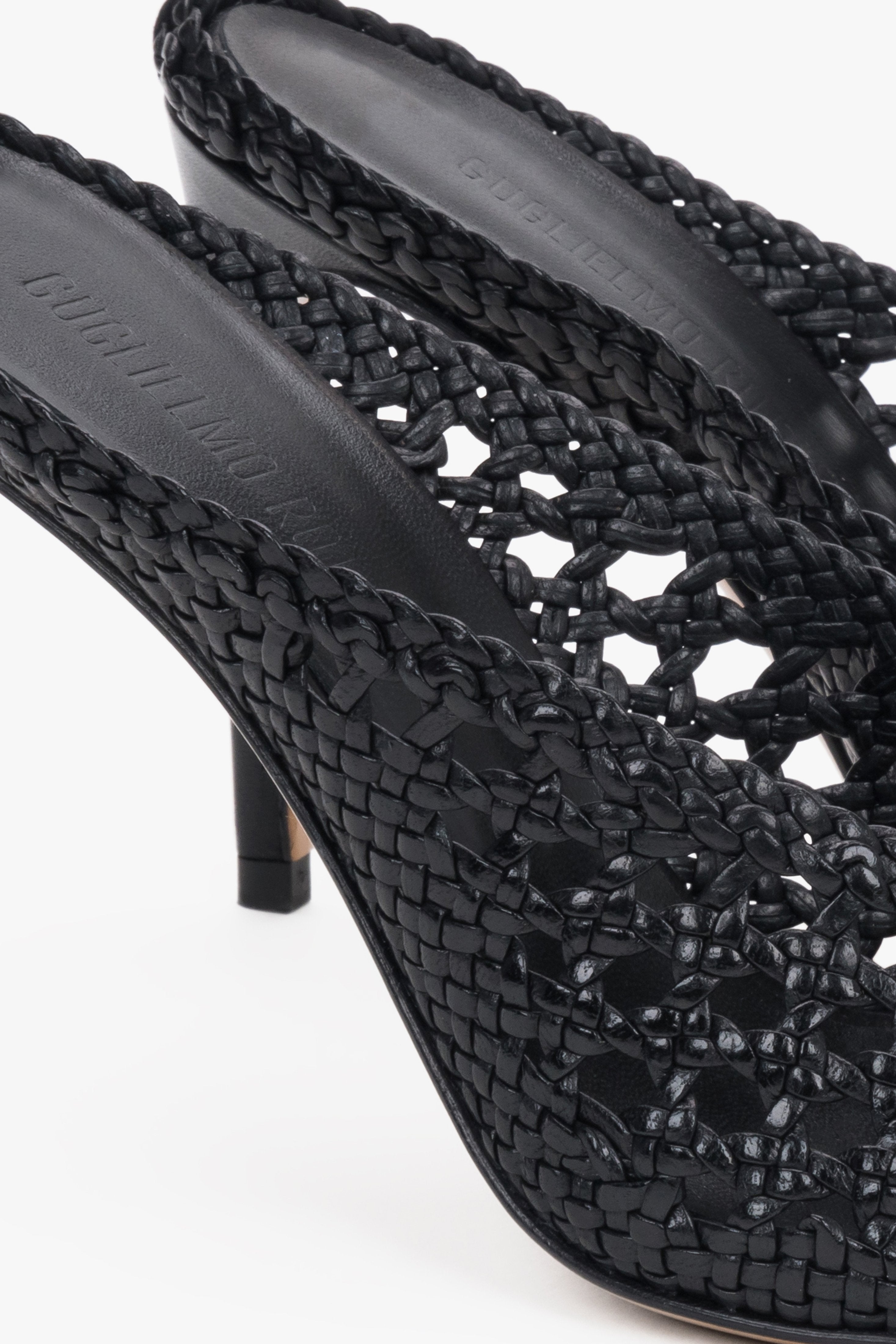 Elegant black woven leather slides featuring an intricate openwork strap and square toe.