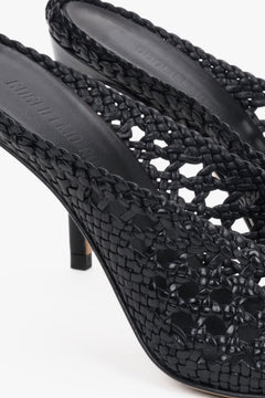 Elegant black woven leather slides featuring an intricate openwork strap and square toe.