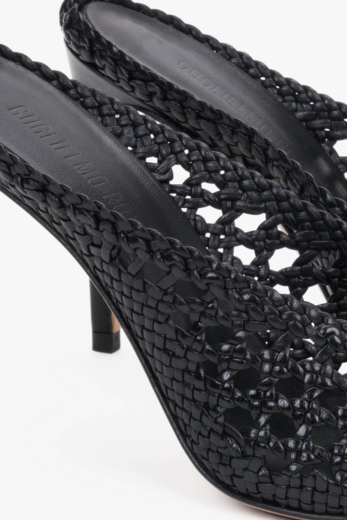 Elegant black woven leather slides featuring an intricate openwork strap and square toe.