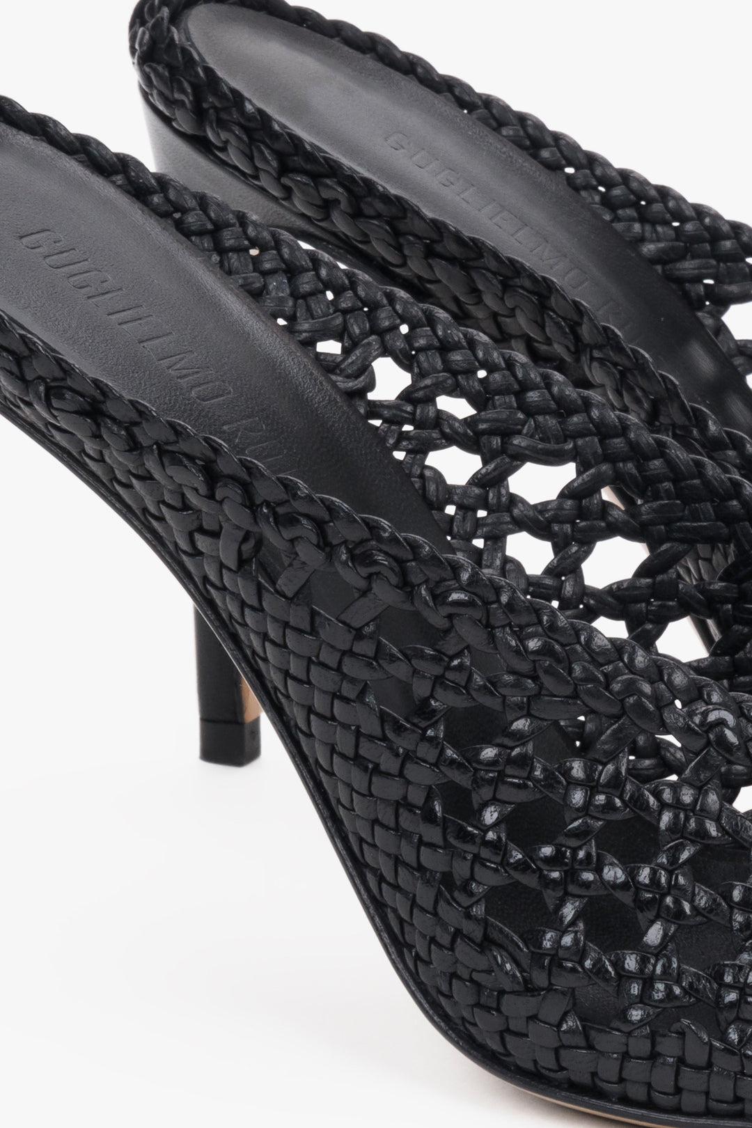 Elegant black woven leather slides featuring an intricate openwork strap and square toe.