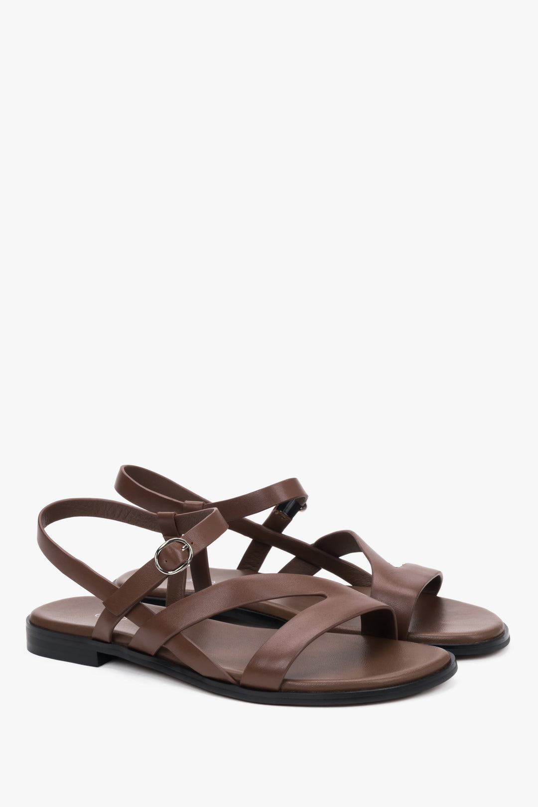 Brown women’s leather sandals with crisscross straps and a flat sole.