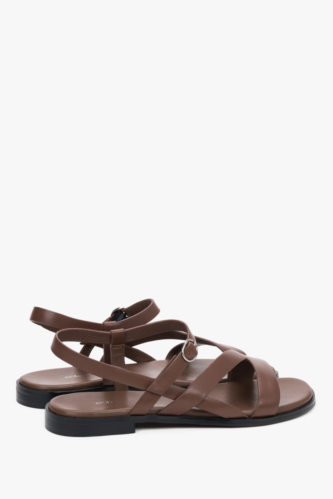 Brown women’s Estro leather sandals with crisscross straps and a flat sole.