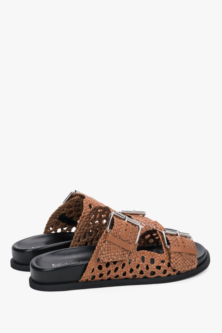 Close-up of the perforated brown leather and artisanal stitching on premium slides.