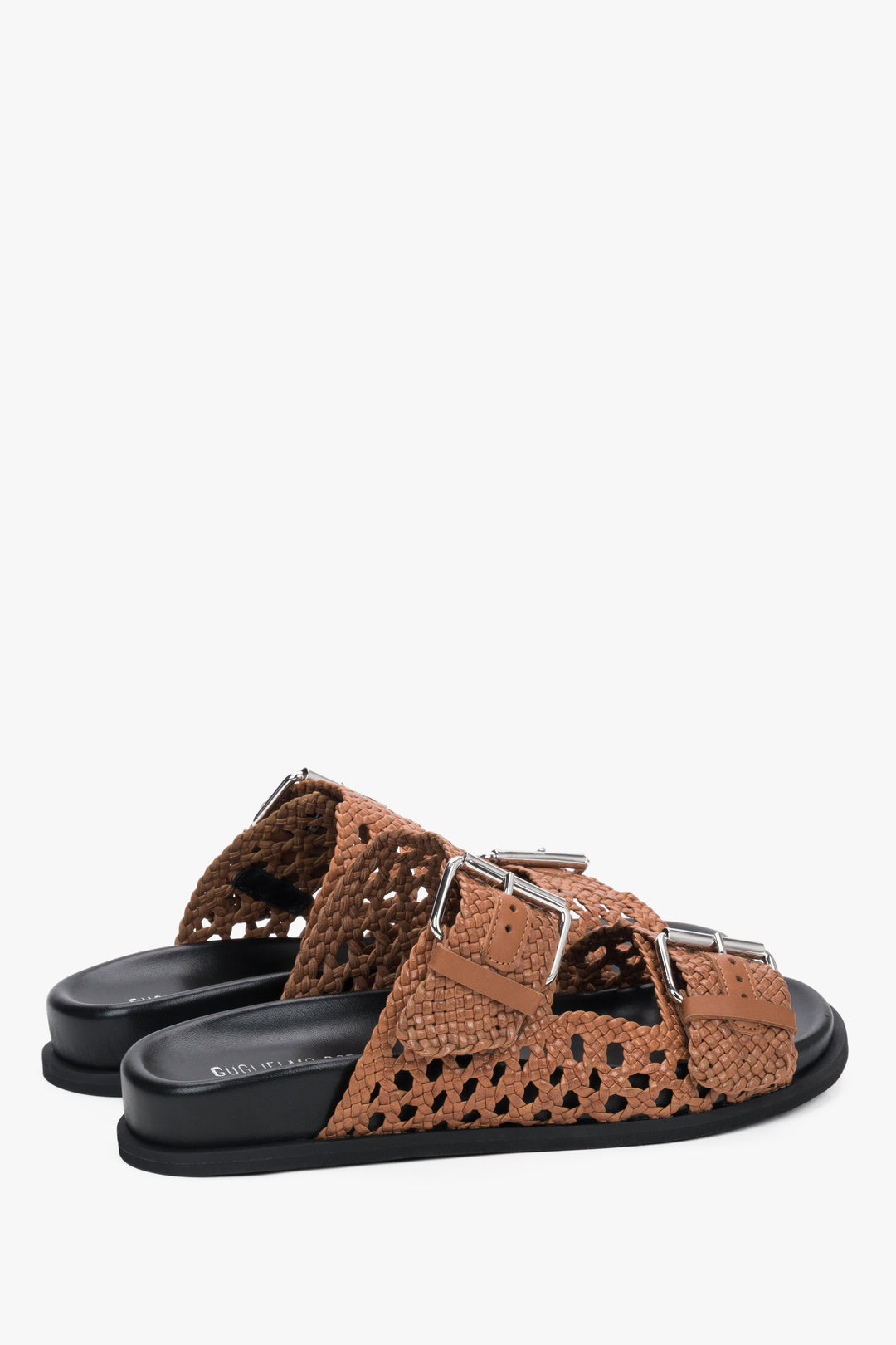 Close-up of the perforated brown leather and artisanal stitching on premium slides.