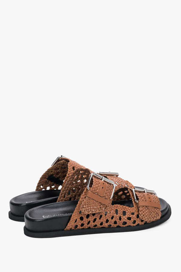 Close-up of the perforated brown leather and artisanal stitching on premium slides.