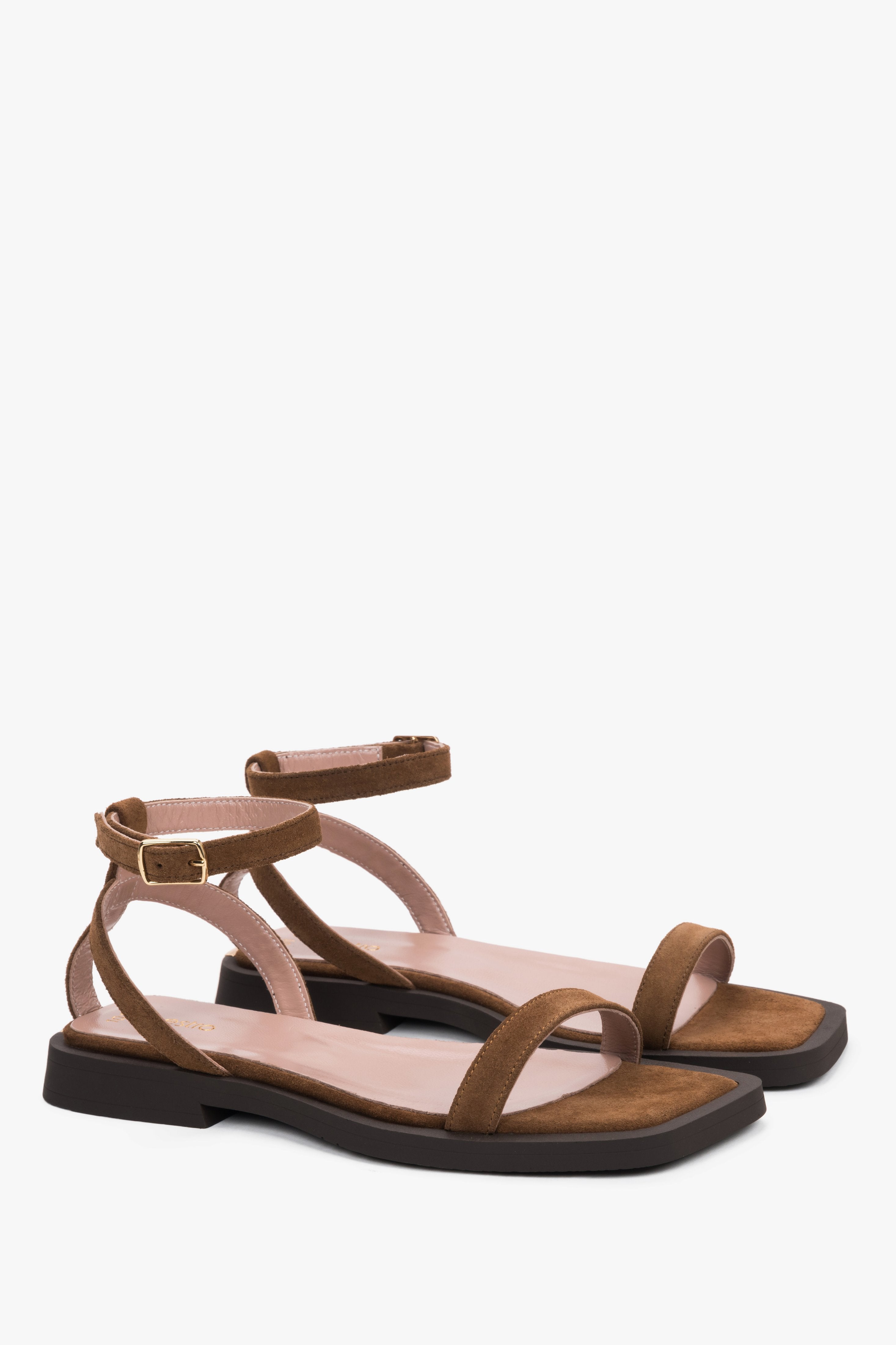 Side view of women’s brown flat sandals with delicate thin straps.