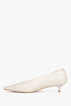 Side view of the pointed toe and smooth leather trim on cream and beige kitten heel sandals.