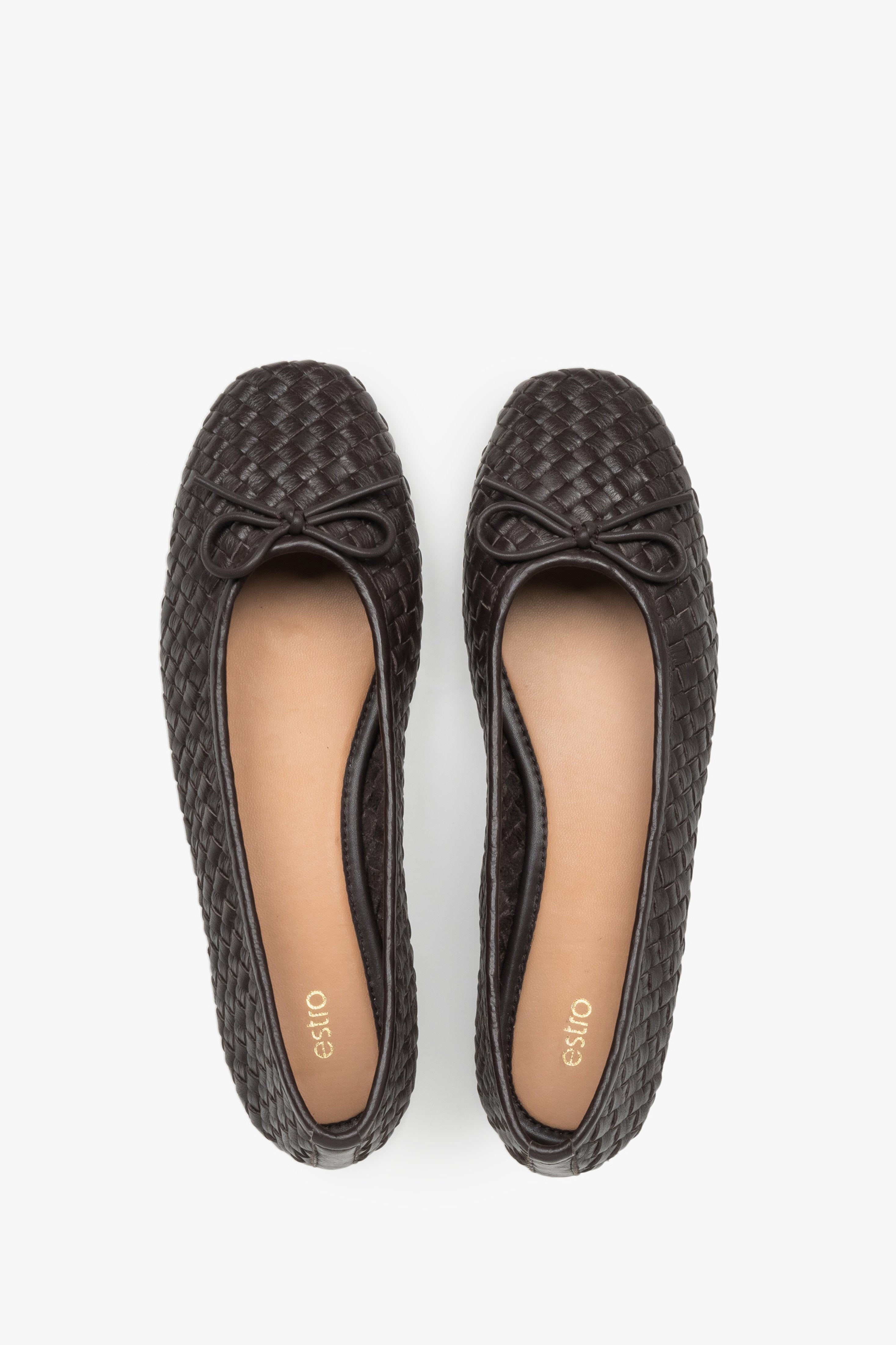 View of a pair of shoes, showcasing a refined toe with a decorative bow and a smooth light-toned leather insole in a contrasting shade.