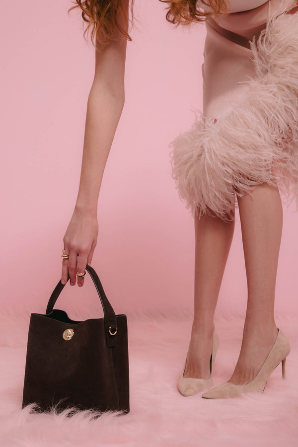 Dark brown women’s velour handbag by Estro, carried by hand.