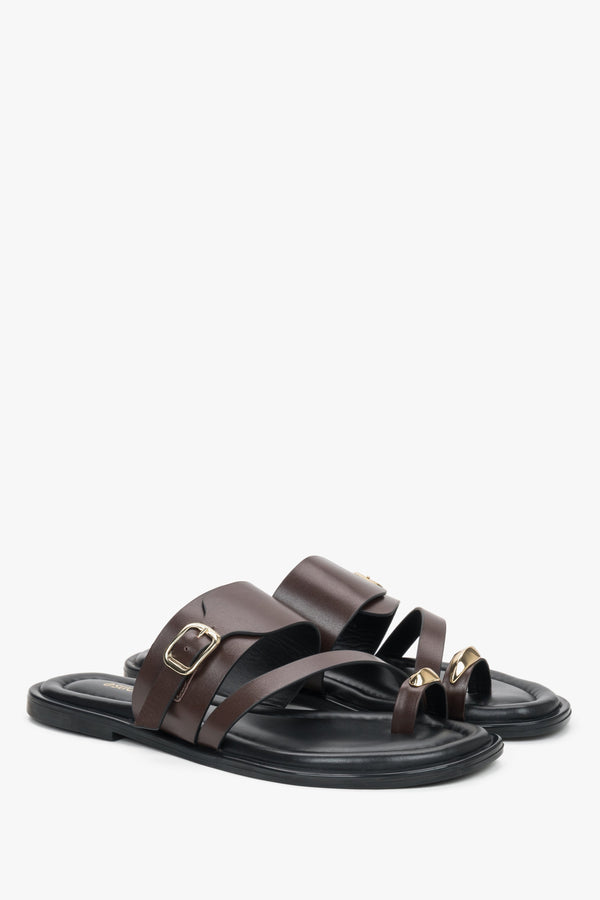 Dark brown leather Estro mules with a toe loop, showcasing an asymmetrical upper line and a bold gold buckle detail.