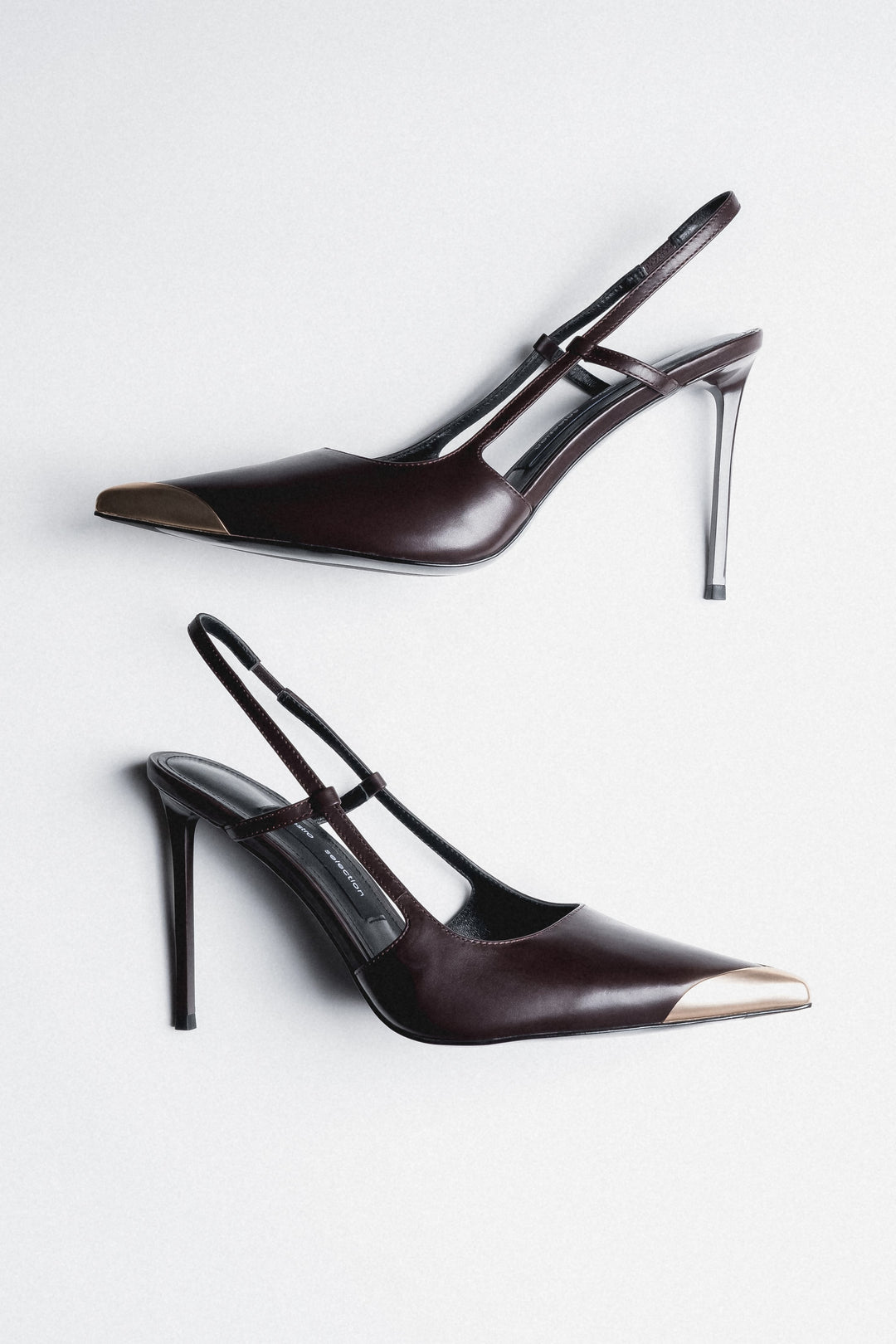 Side view of women's dark brown leather slingback stilettos with gold pointed toe