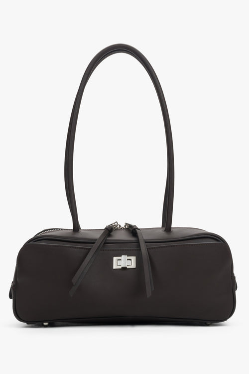 Dark brown natural leather shoulder baguette bag. Slim silhouette and decorative pull tabs at the zippers.