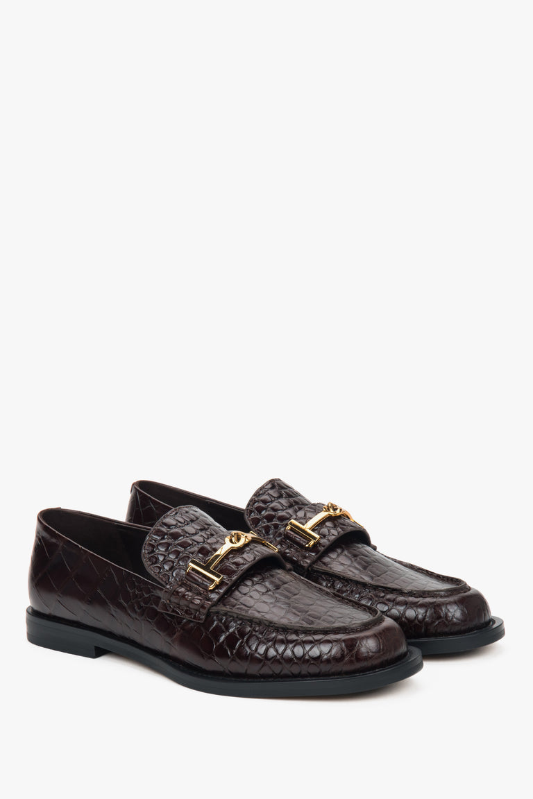 Dark brown women’s patent leather loafers with a decorative buckle.