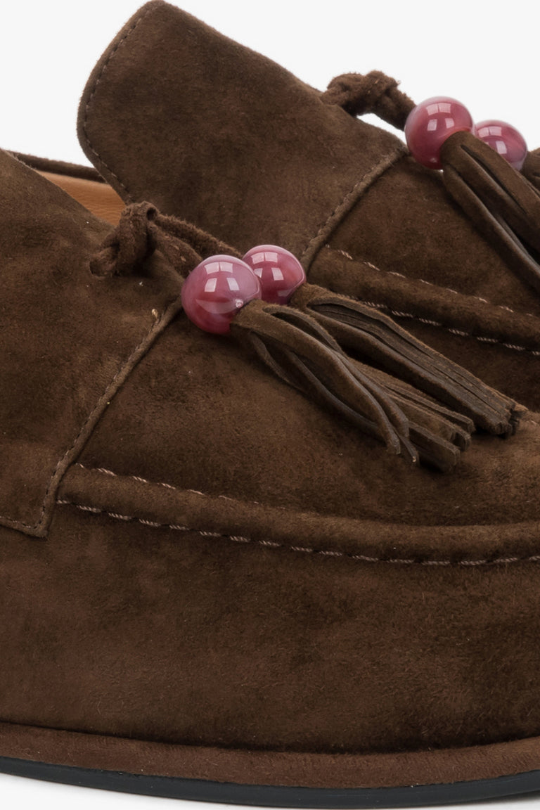 A close-up shot of the front of the shoe, displaying the artisanal decorative tassel with a bead and the luxurious, matte texture of the dark brown velour.