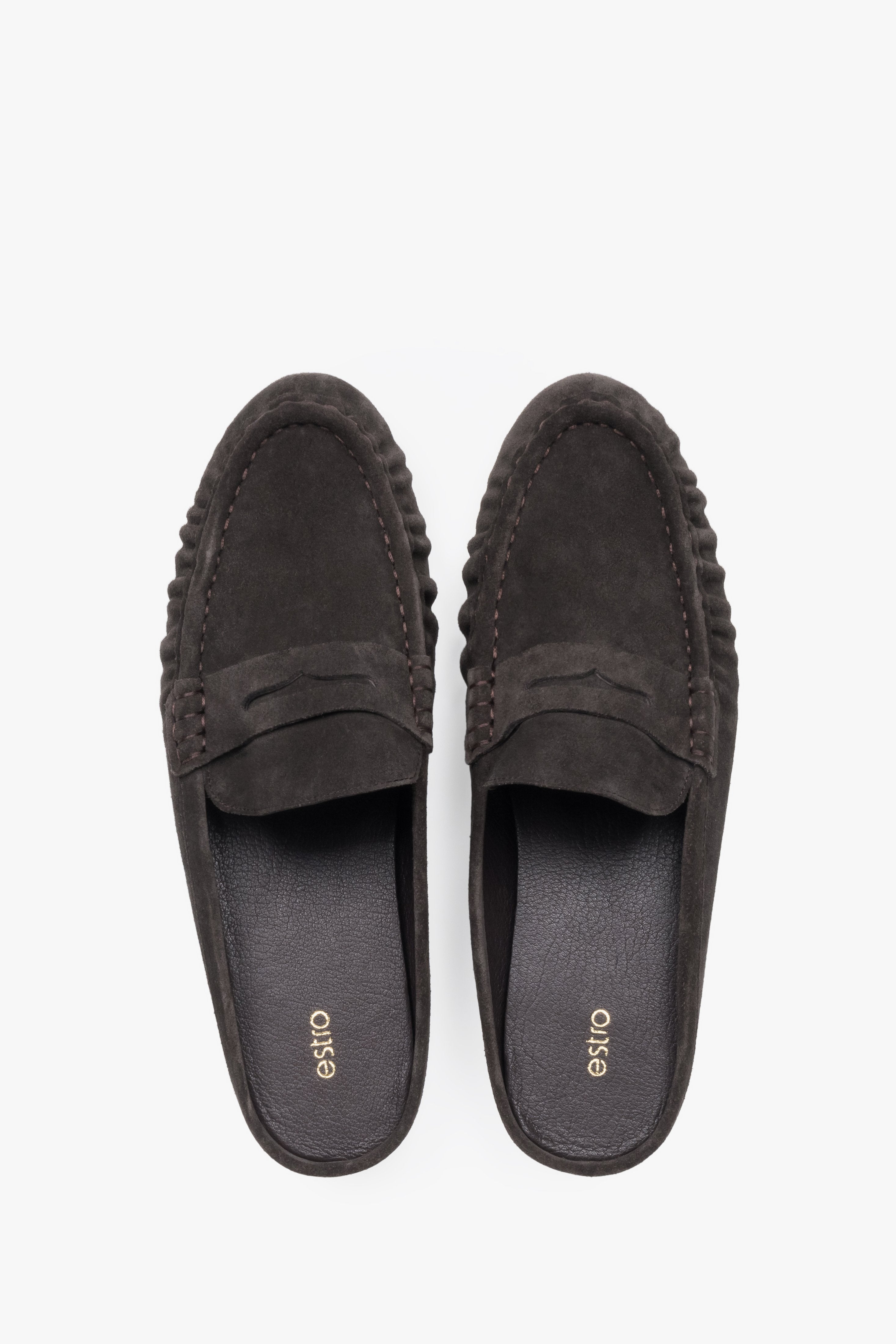 A pair of mules displayed to highlight the loafer-style closed front with a decorative cross strap and a sleek, dark-colored insole.