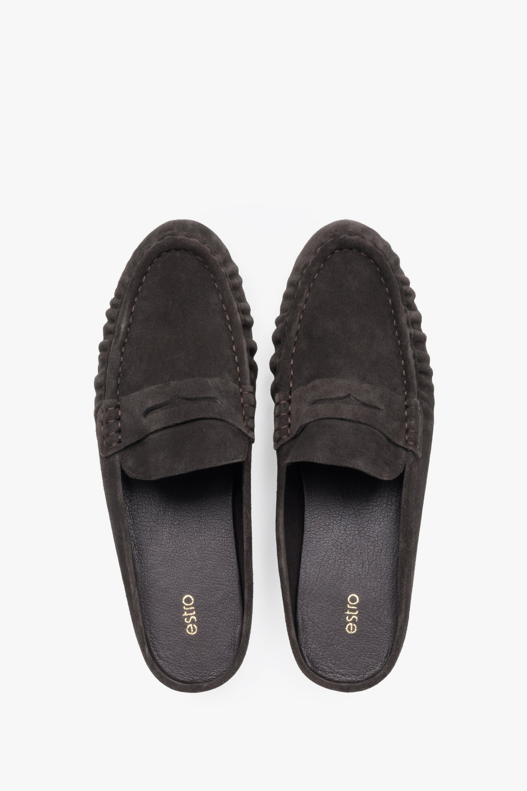 A pair of mules displayed to highlight the loafer-style closed front with a decorative cross strap and a sleek, dark-colored insole.