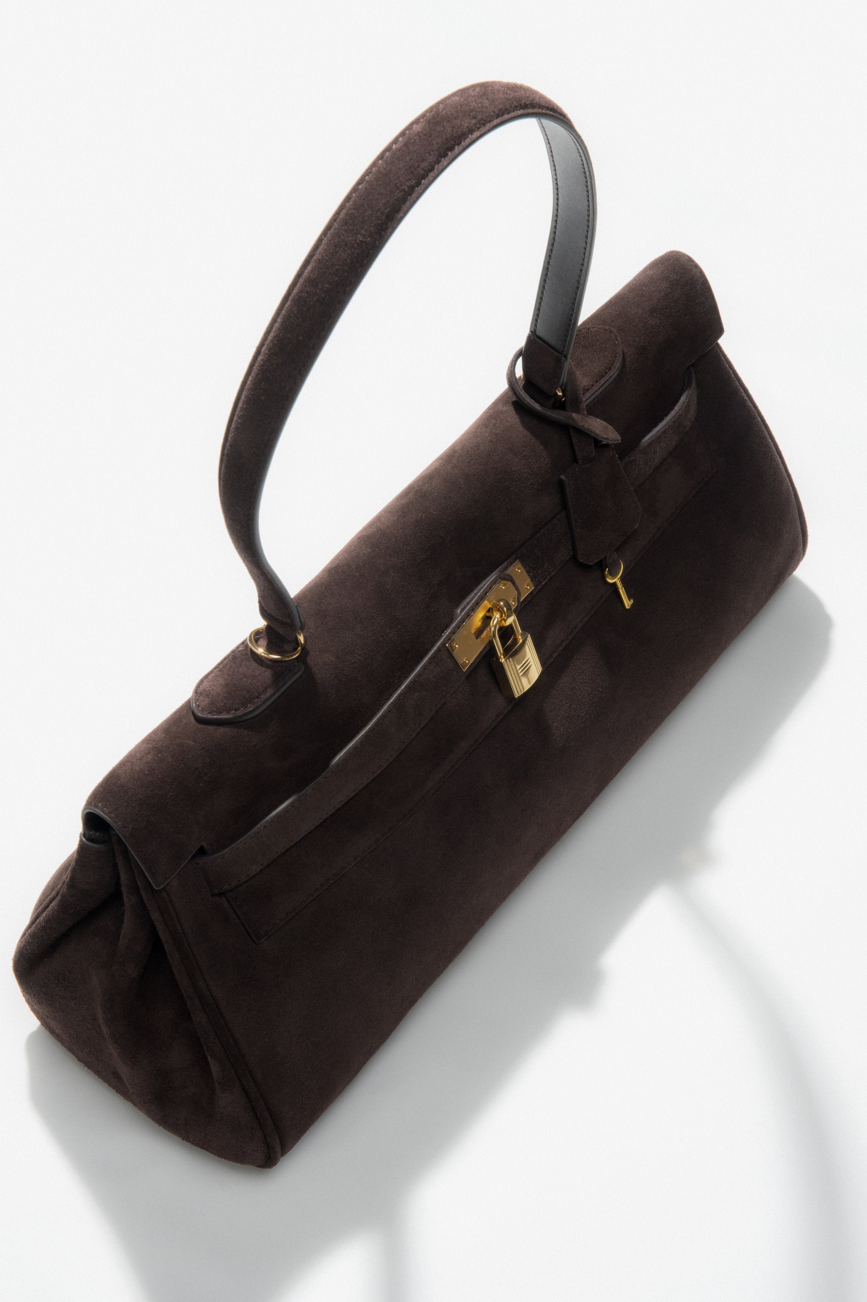 With gold hardware — a dark brown women’s velour shoulder bag by Estro.