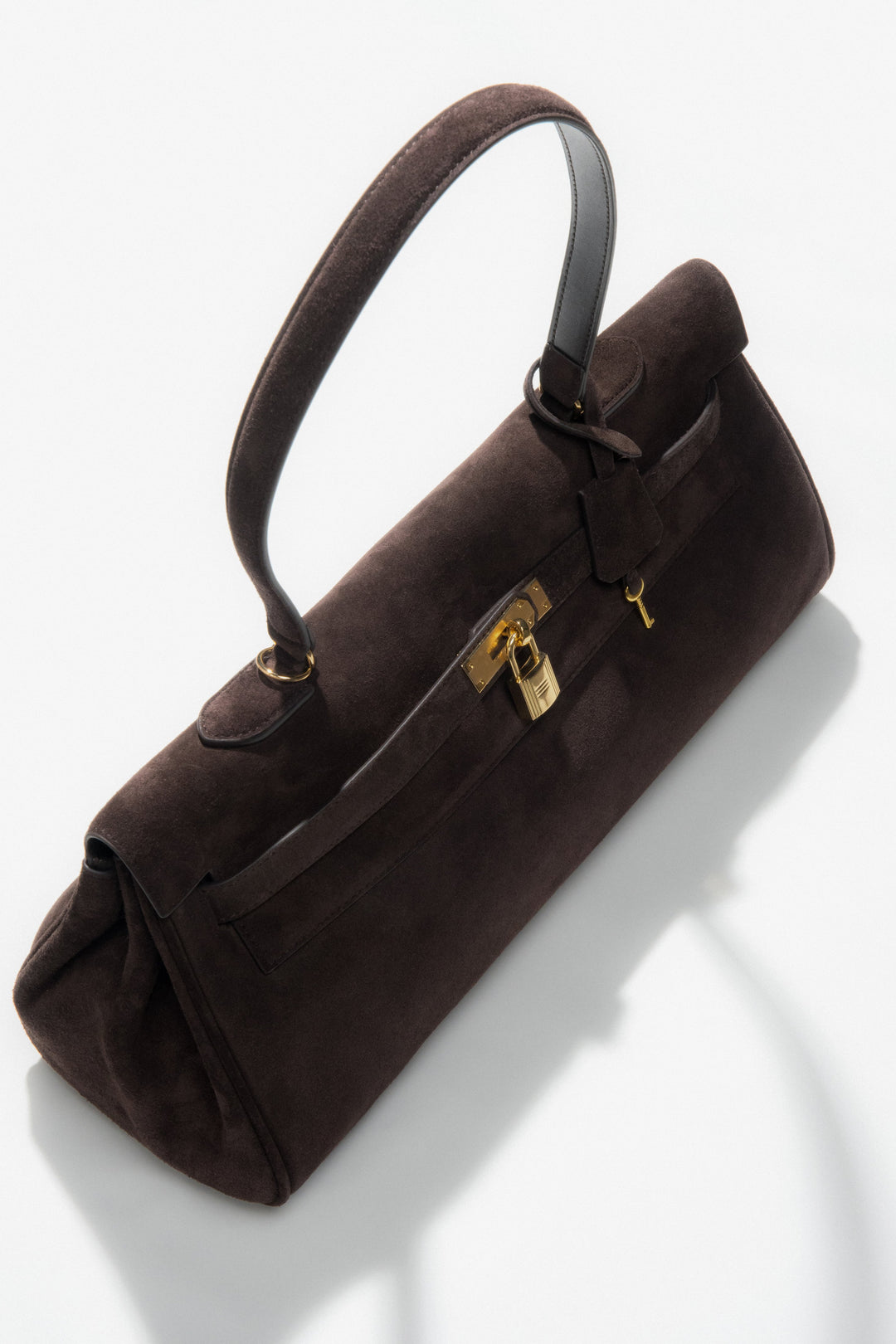 With gold hardware — a dark brown women’s velour shoulder bag by Estro.