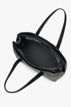 Stylish black tote bag with dual handles and adjustable shoulder strap, fits A4.