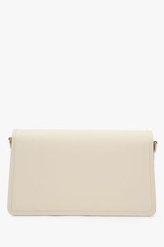 Close-up of the gold-tone snap closure on a milky beige natural leather bag.