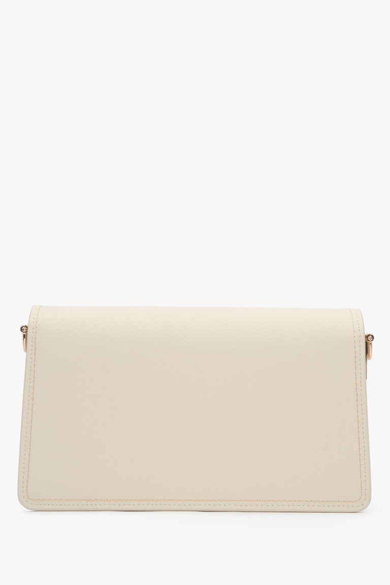 Close-up of the gold-tone snap closure on a milky beige natural leather bag.