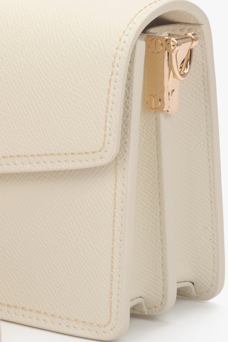 Compact off-white leather bag with a functional zipper and adjustable shoulder strap.